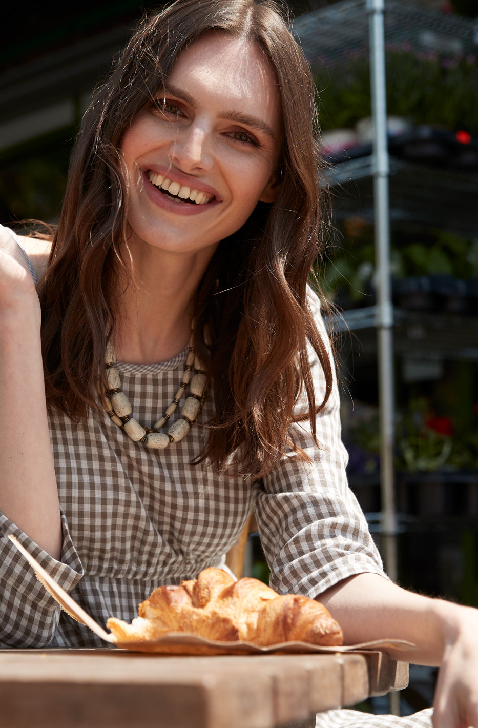 Happy woman wearing a tunic top and some food on a wooden table.