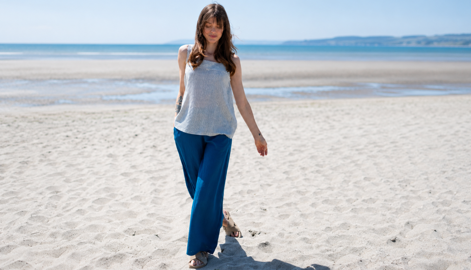 Woman wearing sustainable viscose wide-leg trousers styled with a breathable top for an effortless summer outfit from Nomads Clothing.