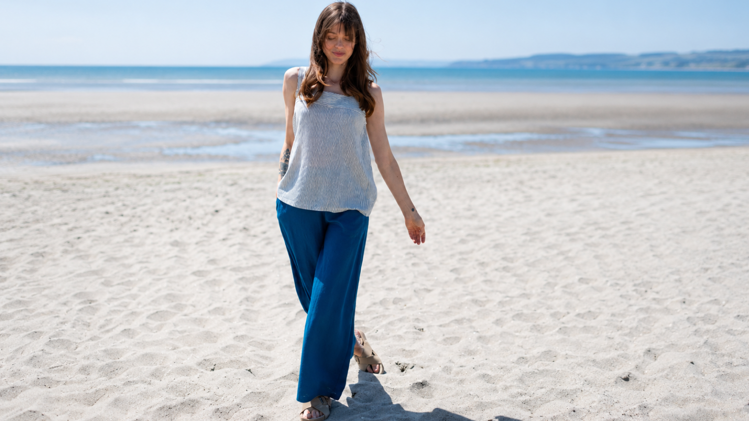 Woman wearing sustainable viscose wide-leg trousers styled with a breathable top for an effortless summer outfit from Nomads Clothing.