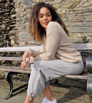 Girl with curly hair sitting on a street bench and wearing a long sleeve cotton top.